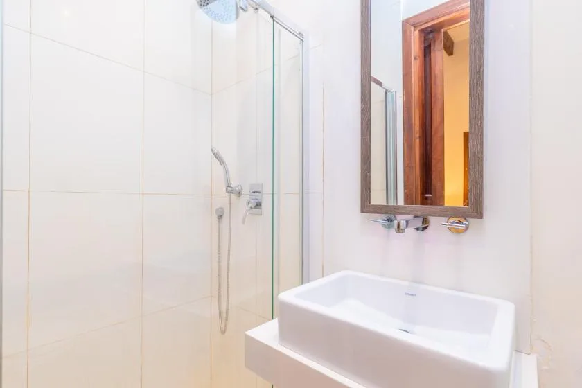 A bright bathroom with a glass shower and a white sink.