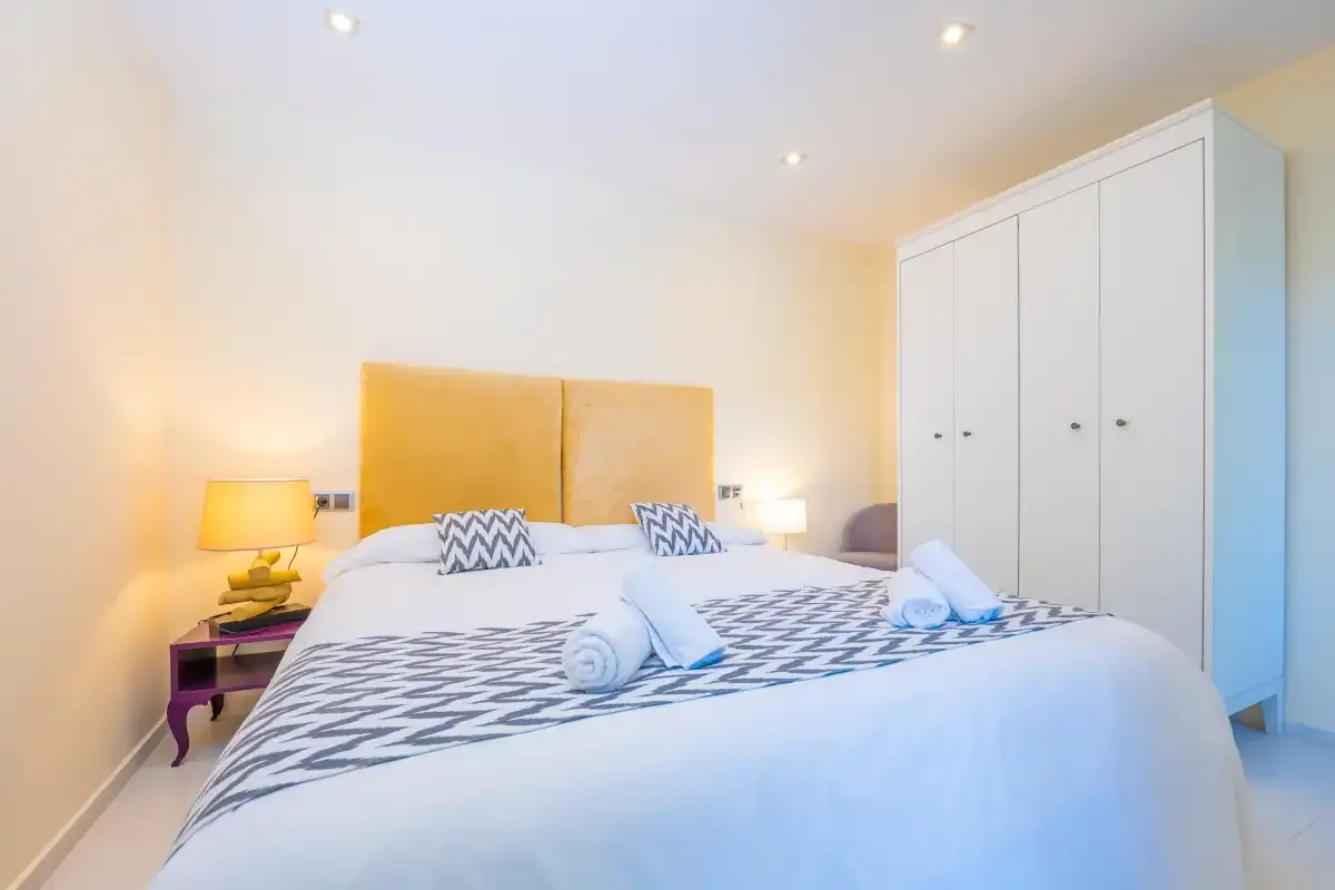A bedroom with a neatly made bed and a wardrobe.