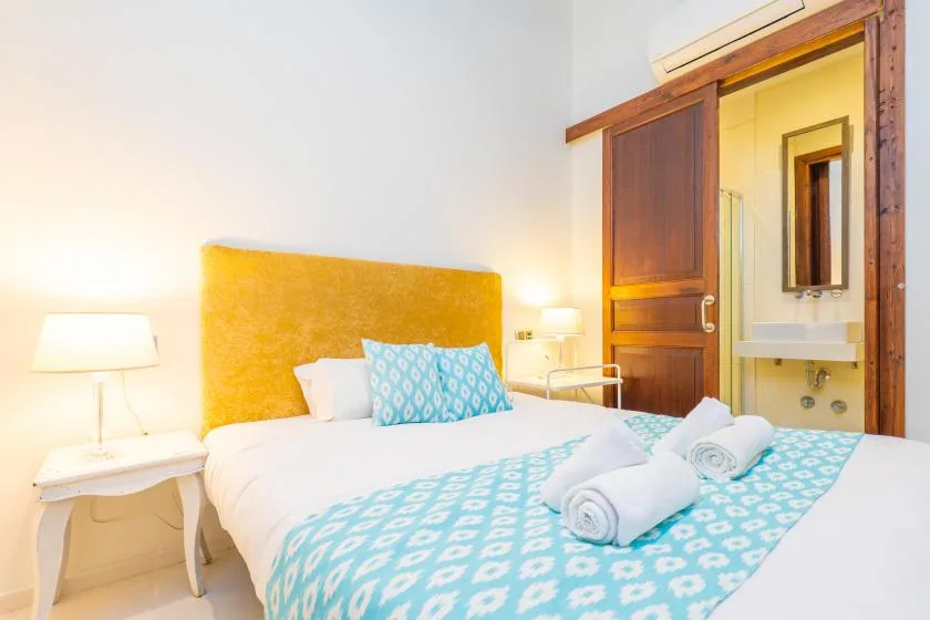 A bedroom with a bed dressed in white and turquoise bedding.
