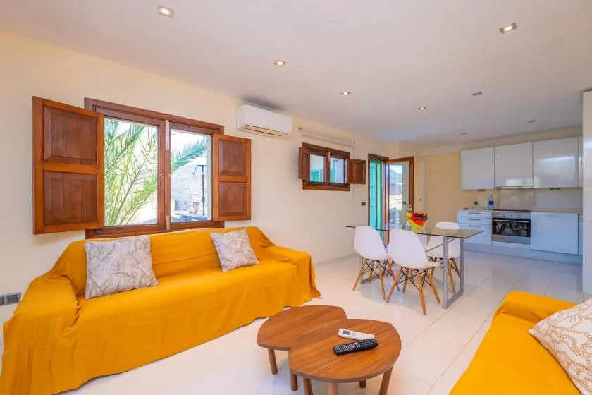 A bright open-plan living room with a yellow sofa and a dining area.