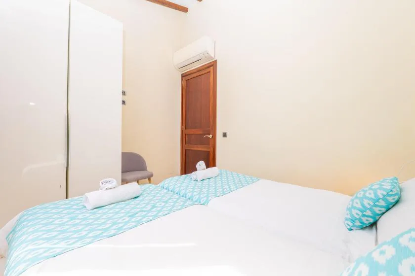 A bedroom with white bedding and turquoise patterned linens.