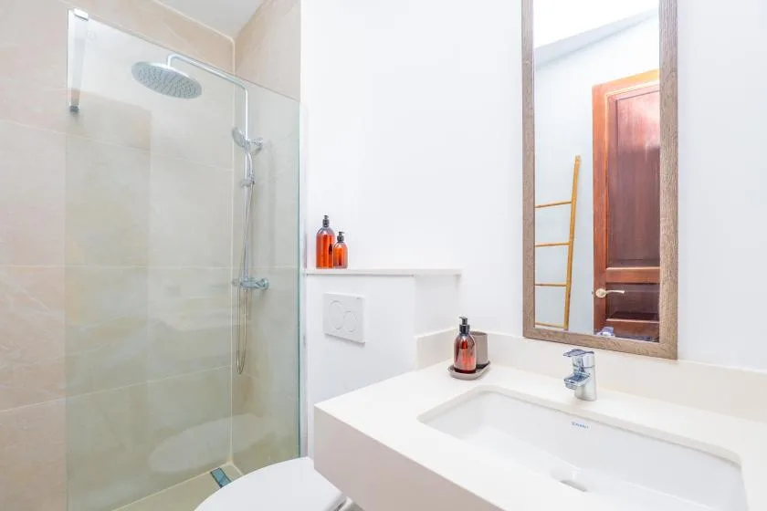 A bright bathroom with a glass shower and a white sink.