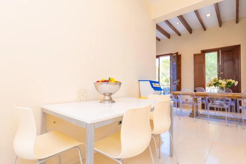 A bright dining area with white tables and chairs, opening onto a second dining space.