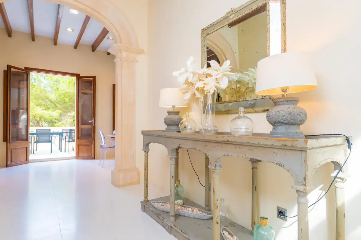 A bright interior with a console table, lamps, and an open doorway to a patio.