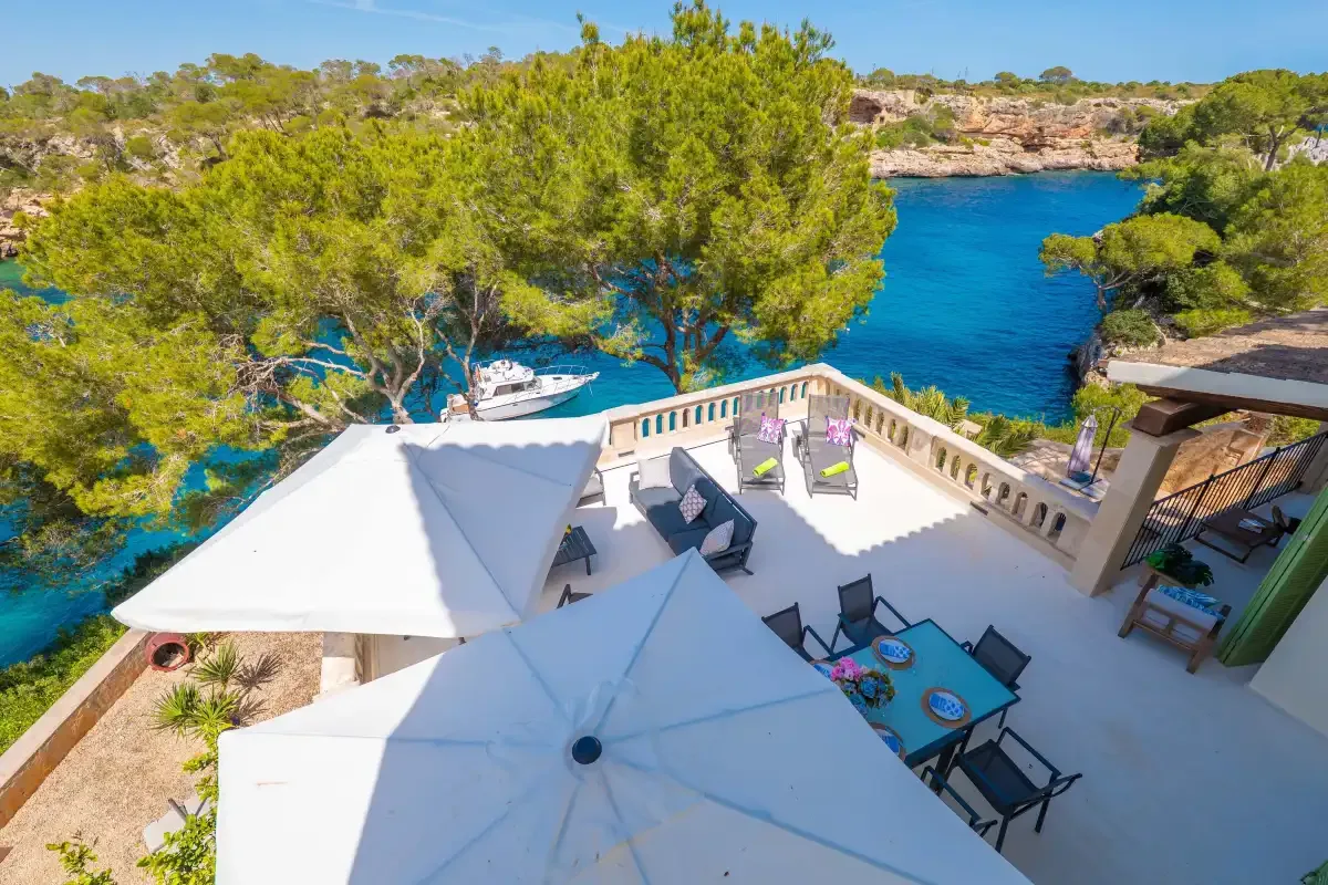 A waterside terrace with seating overlooks a blue inlet.