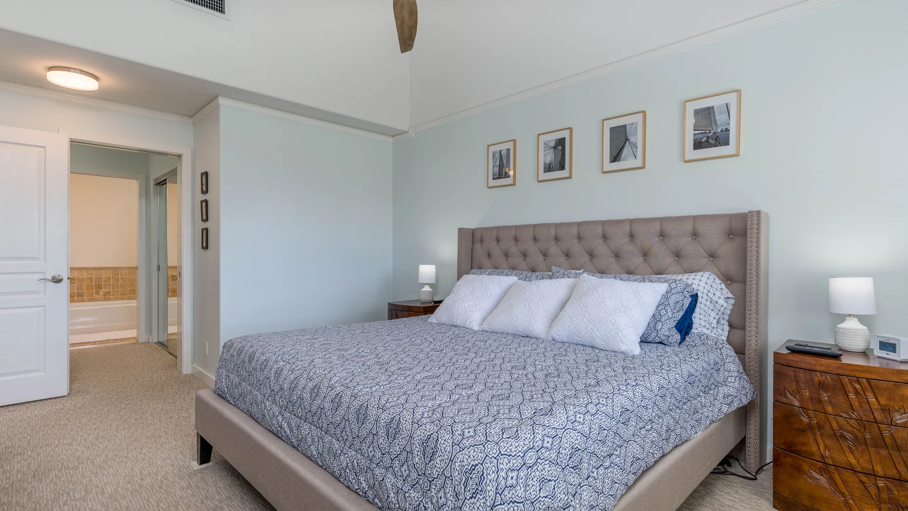 Un dormitorio con una cama grande, ropa de cama estampada y cuadros sobre el cabecero.