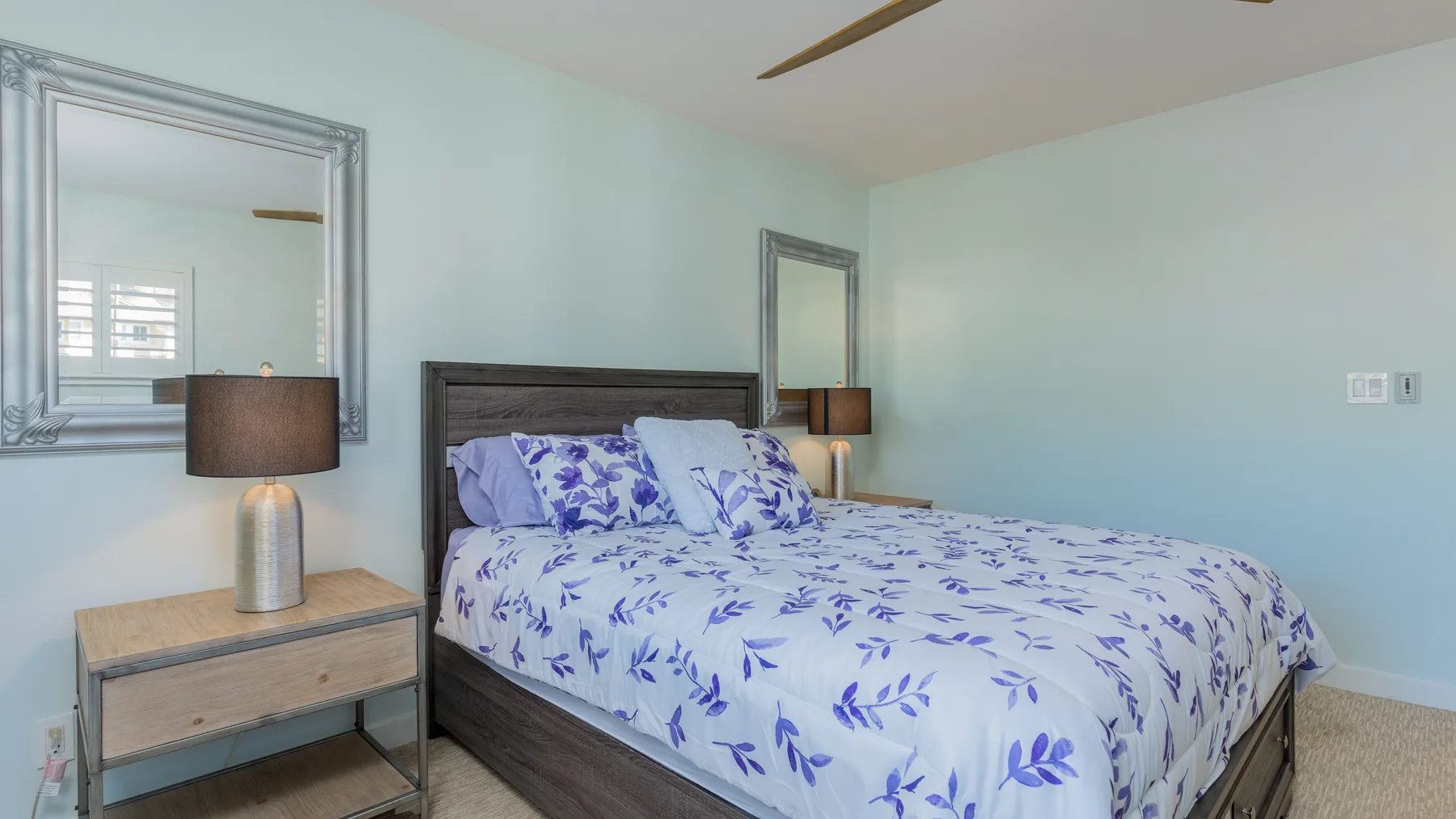 Un dormitorio con una cama cubierta con ropa blanca de estampado floral azul.