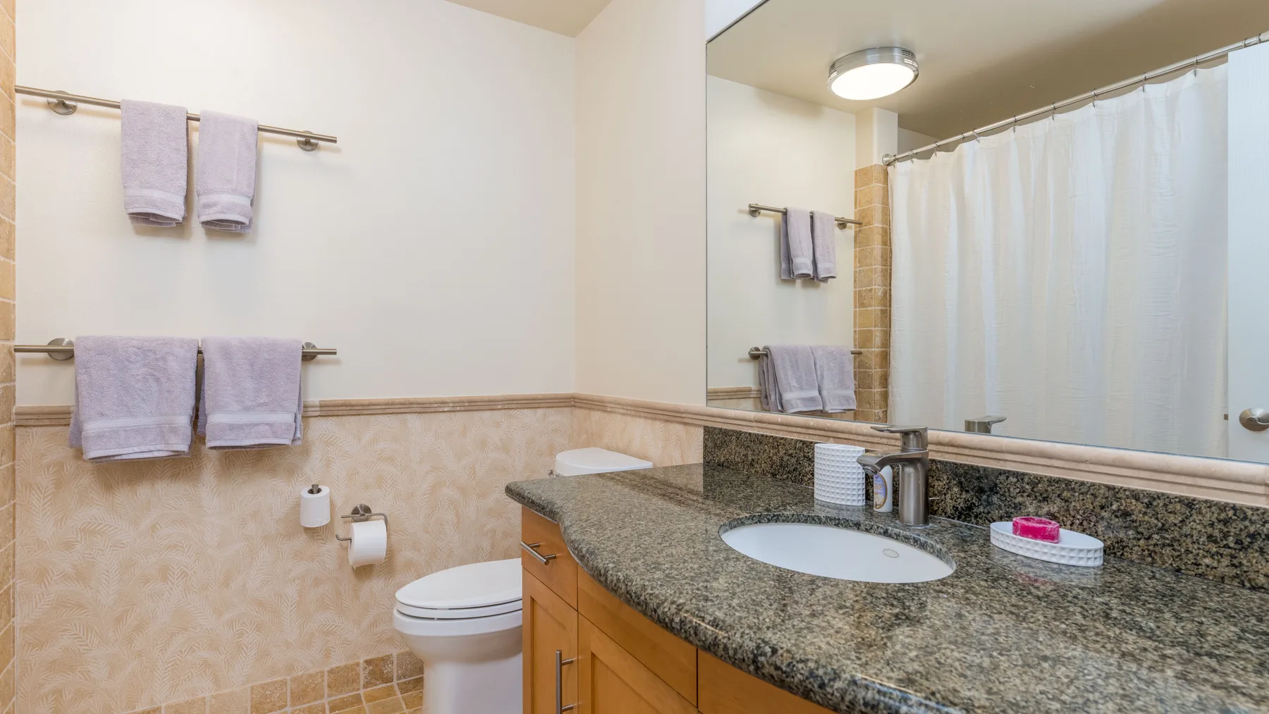 Un baño con lavabo, inodoro y ducha con cortina.