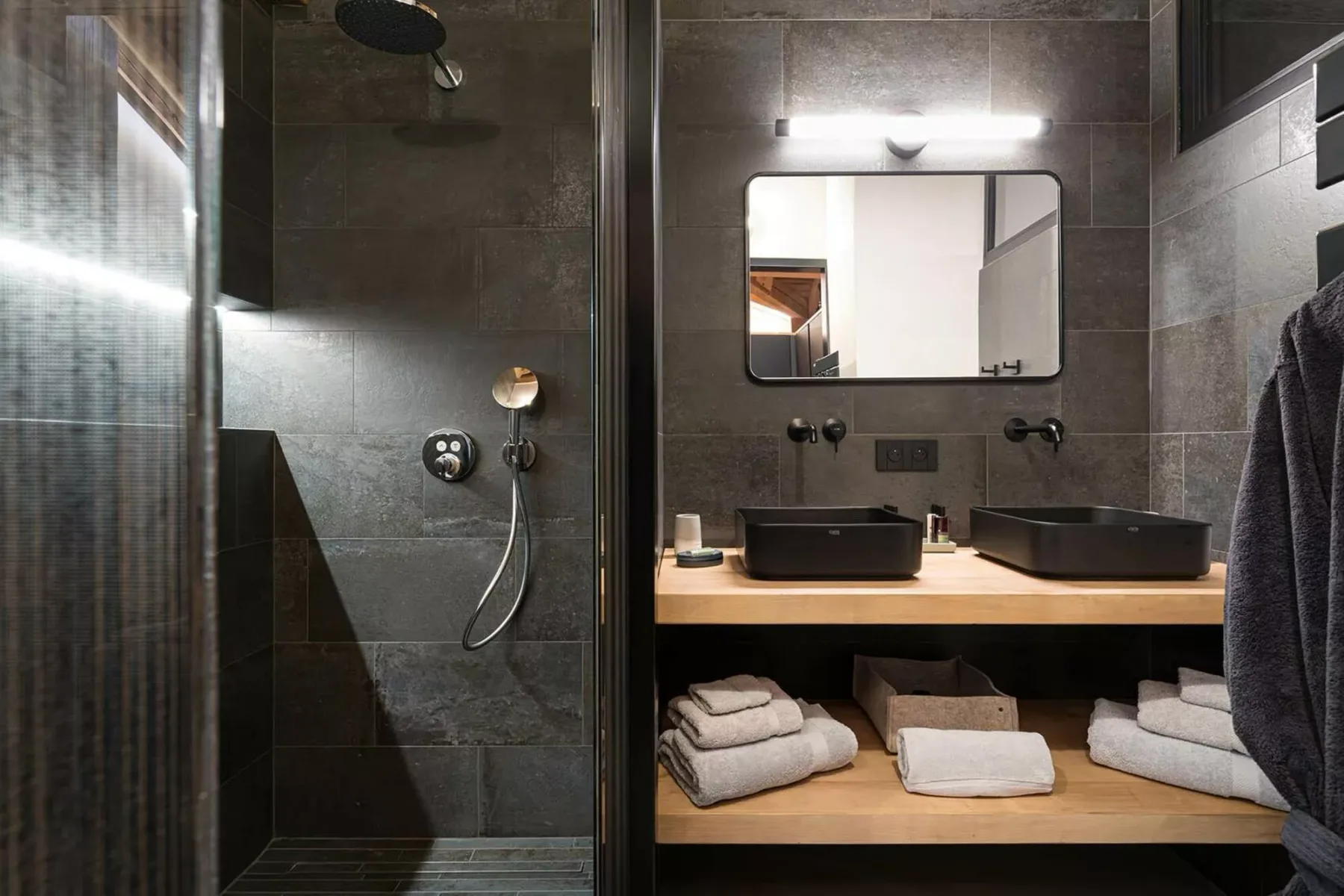 A tiled bathroom with a glass shower and a double-sink vanity.