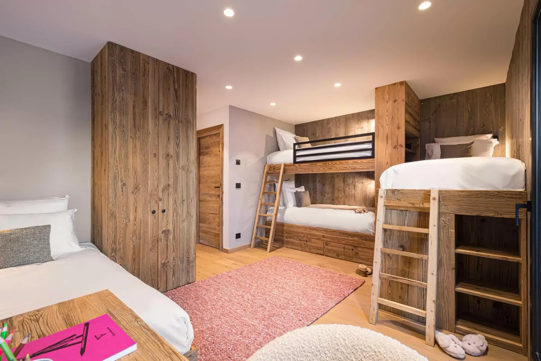 A bedroom with wooden bunk beds and a pink rug.