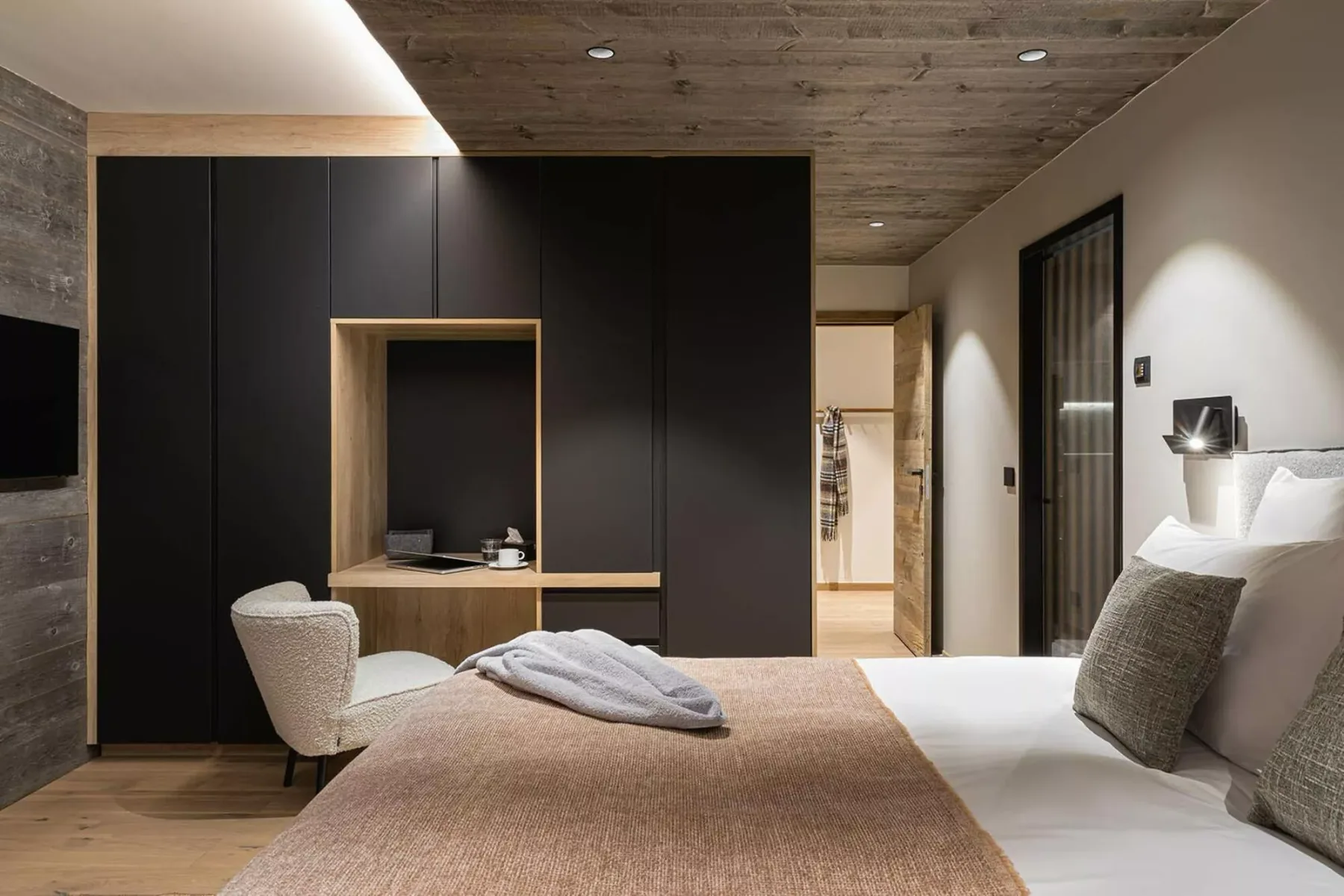 A modern bedroom with a bed and dark built-in cabinetry.