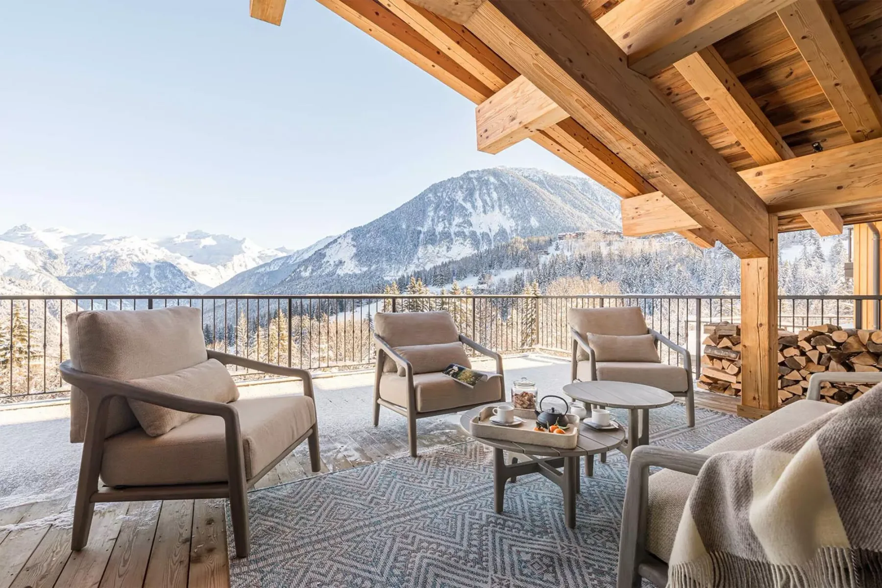 A covered outdoor seating area overlooks a snowy mountain landscape.