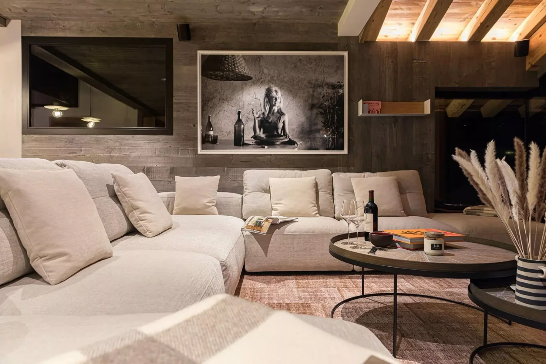 A living room with pale seating, a round coffee table, and a framed wall print.
