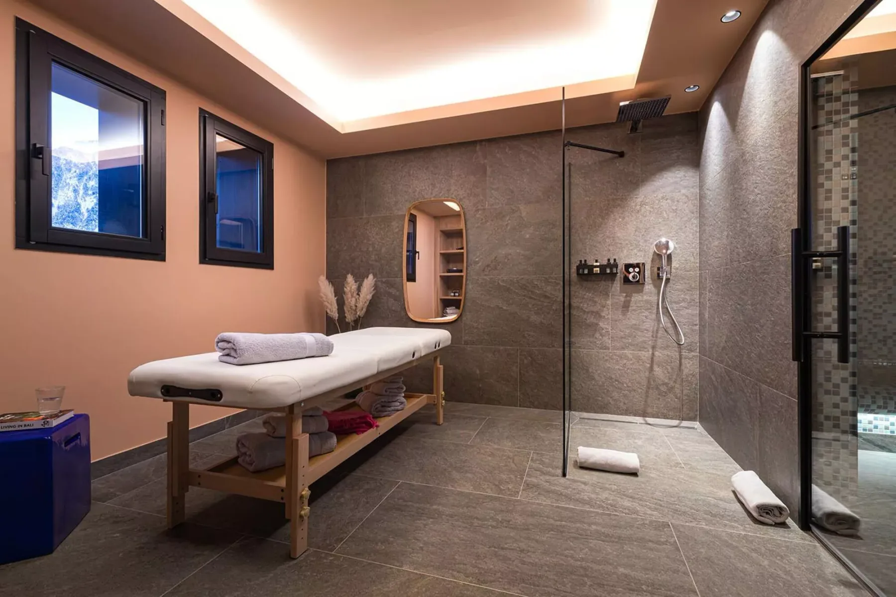 A spa treatment room with a padded massage table beside a walk-in shower.