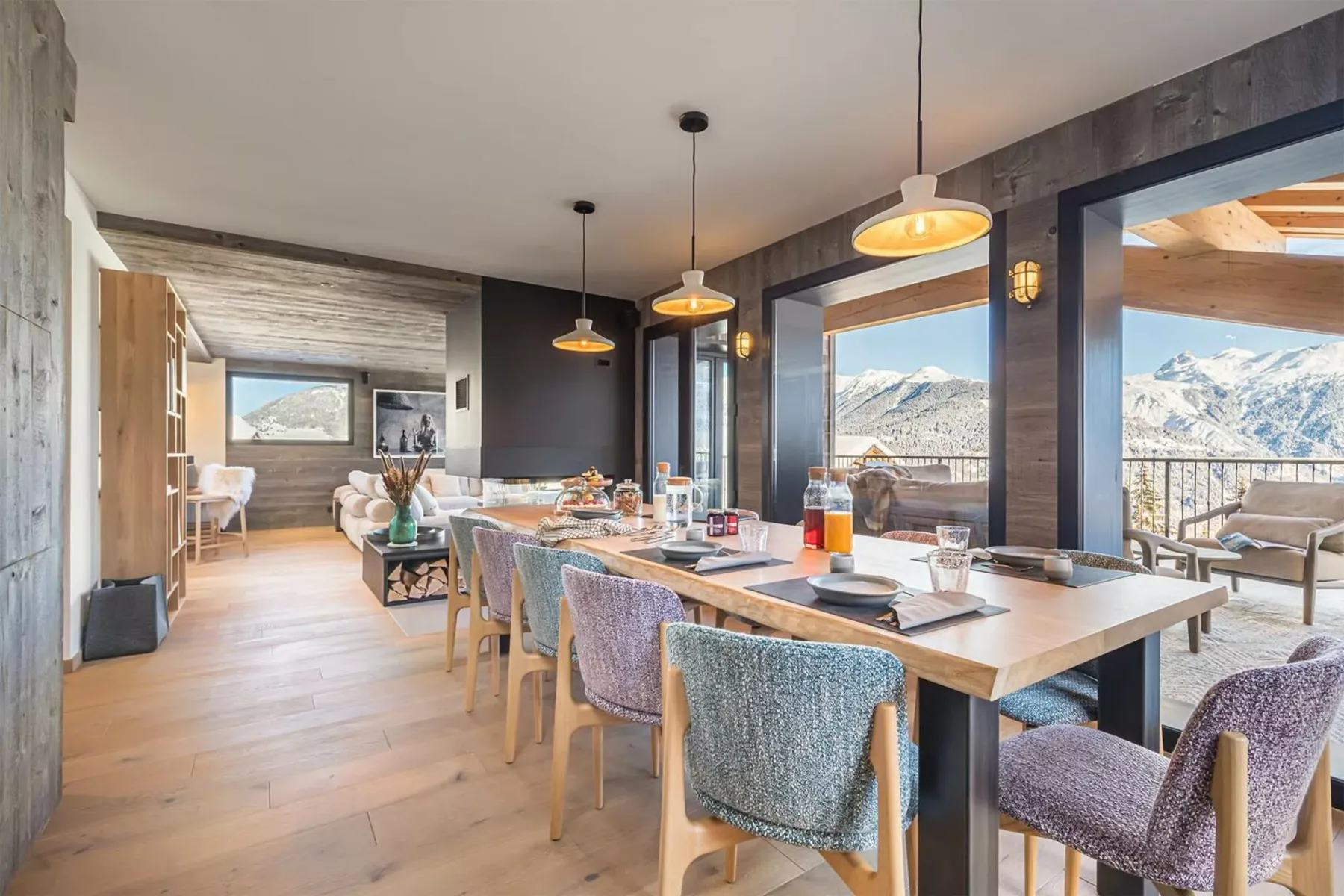 Comedor con una mesa larga y vistas a las montañas a través de grandes ventanales.