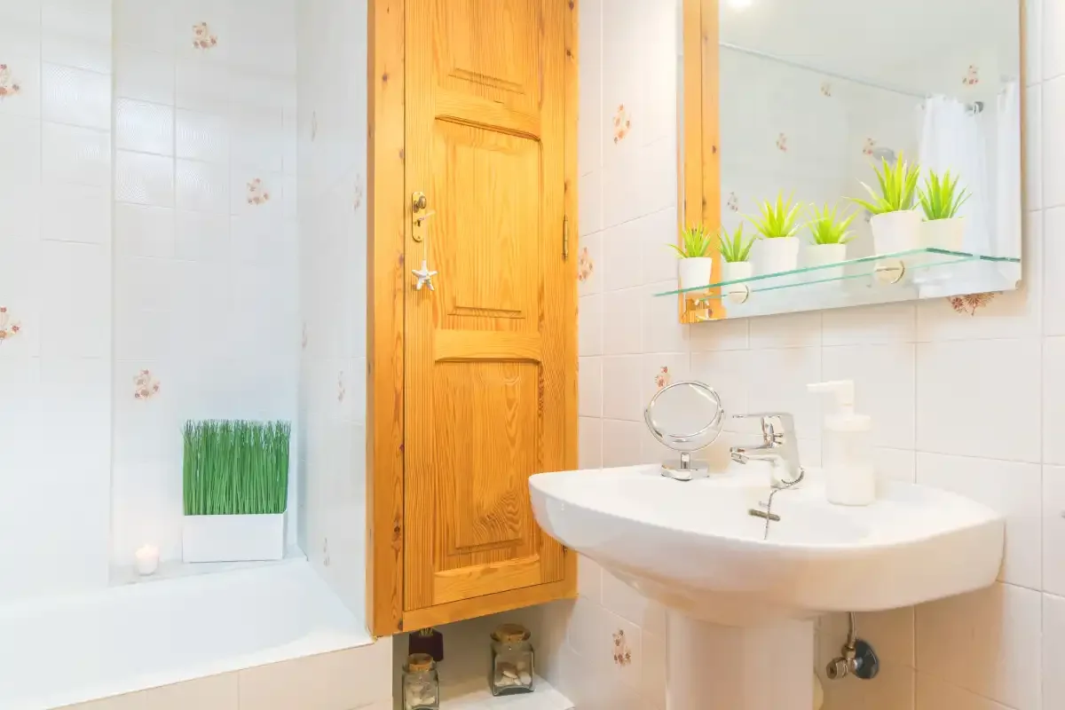 Un baño alicatado con lavabo, espejo y bañera.
