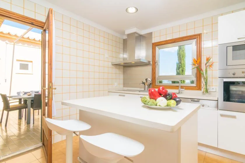Una cocina luminosa con azulejos, una isla central y fruta sobre la encimera.