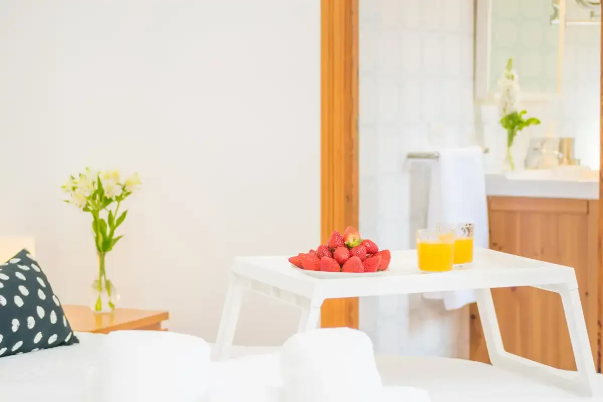 Un comedor luminoso con una mesa blanca con fresas y zumo de naranja.