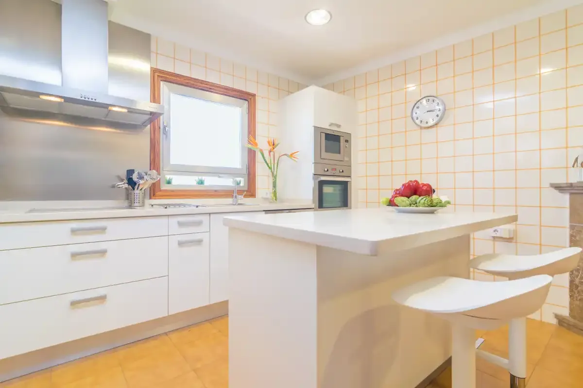 Una cocina luminosa con una isla central y fruta sobre la encimera.