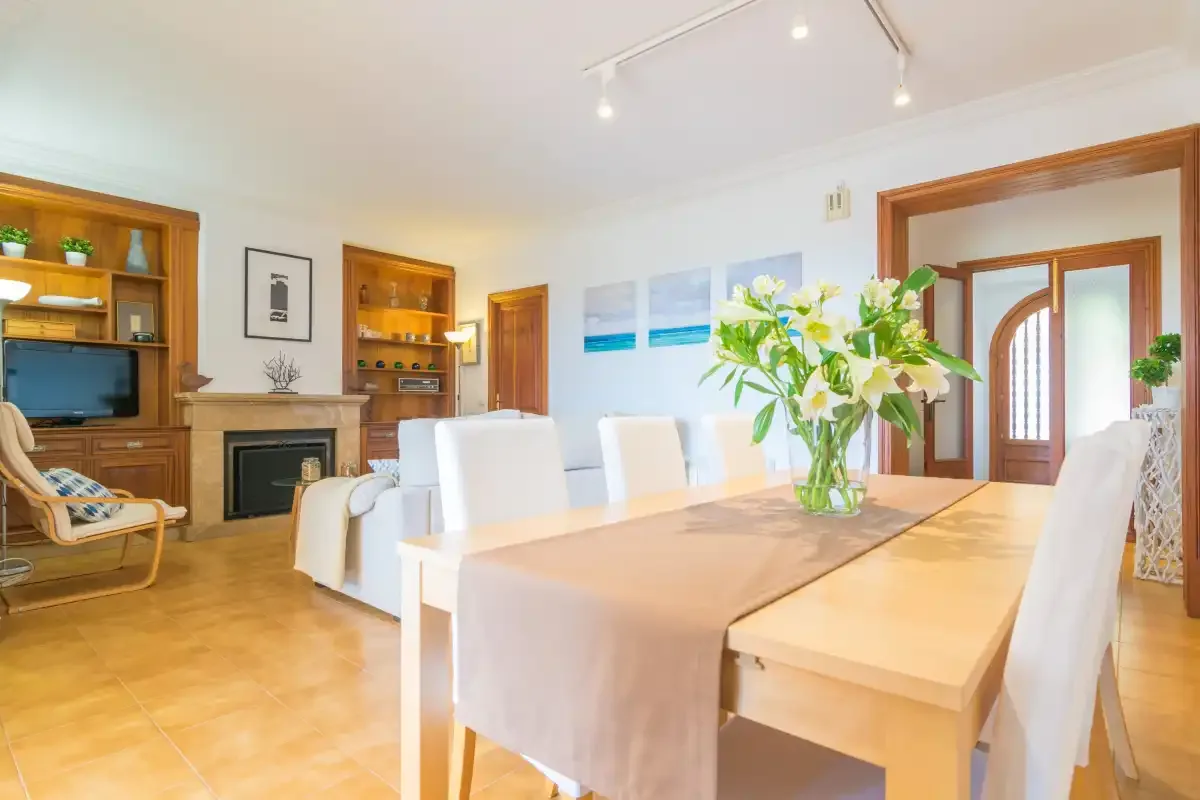 Un comedor luminoso con una mesa larga y una chimenea al fondo.