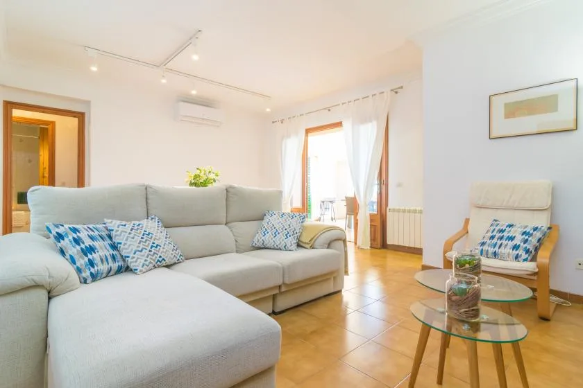Una sala luminosa con asientos seccionales y mesas de centro de vidrio.