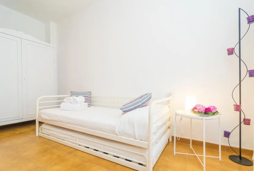 Un dormitorio luminoso con una cama individual blanca y una mesita auxiliar.