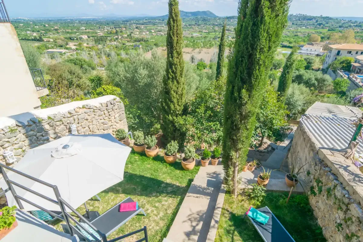 Un jardín ajardinado con altos cipreses ofrece vistas a un amplio valle.