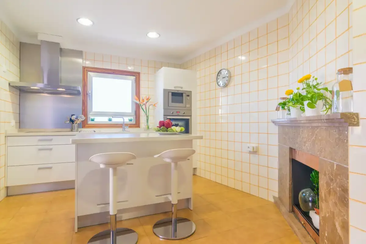 Una cocina alicatada con una isla central y dos taburetes.