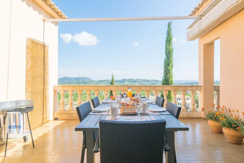Una zona de comedor al aire libre con mesa y sillas da a un paisaje lejano.