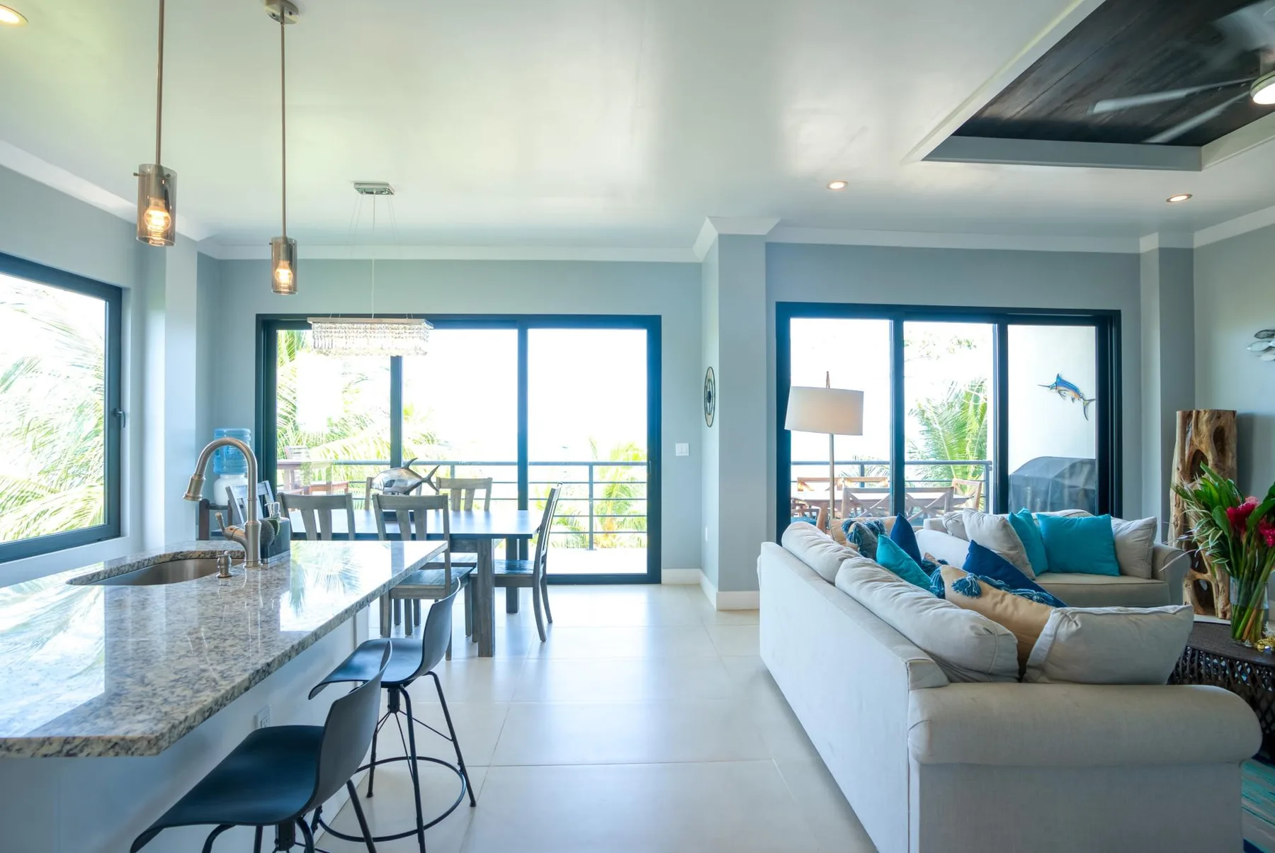 Una luminosa sala-comedor de concepto abierto con isla de cocina y grandes ventanales.