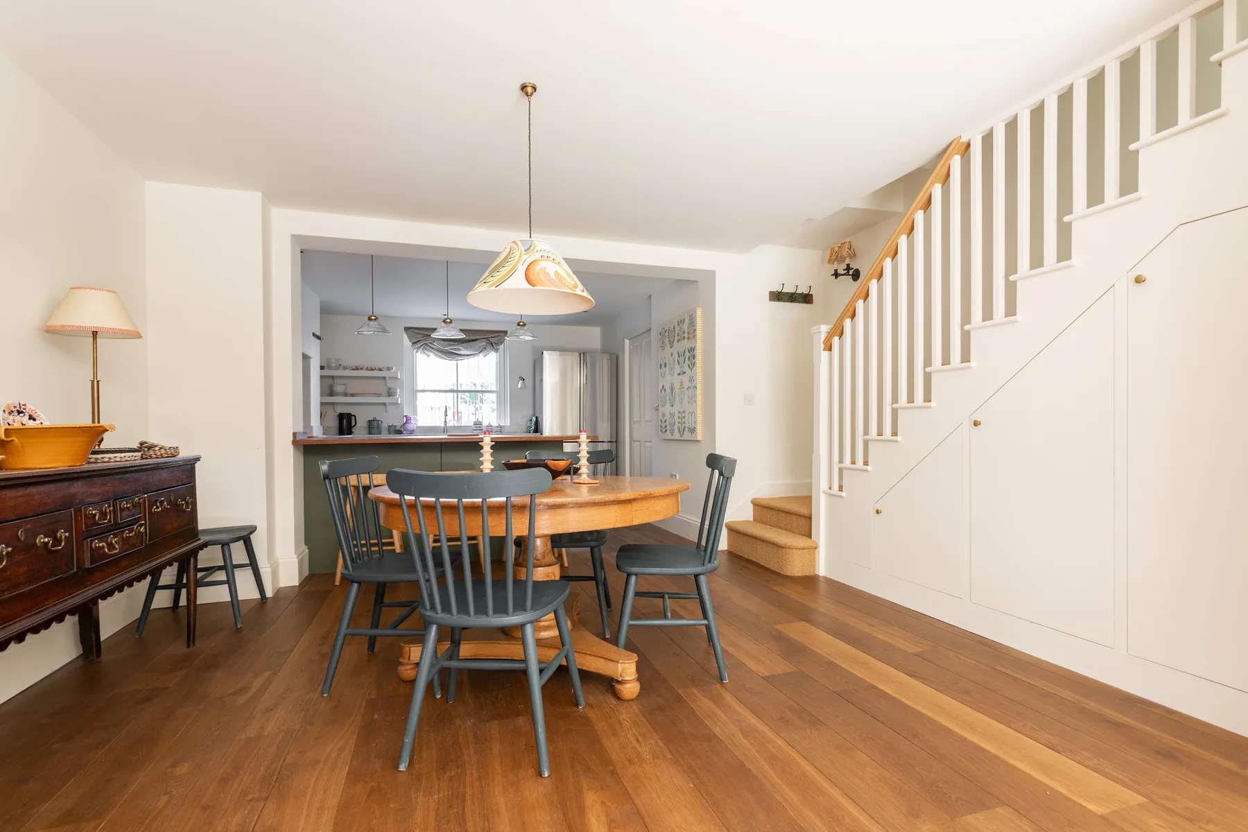 Un comedor con una mesa de madera y sillas junto a una escalera.
