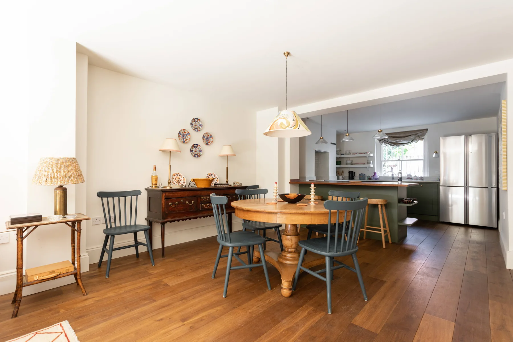 Un comedor abierto a la cocina, con una mesa de madera y encimeras visibles.