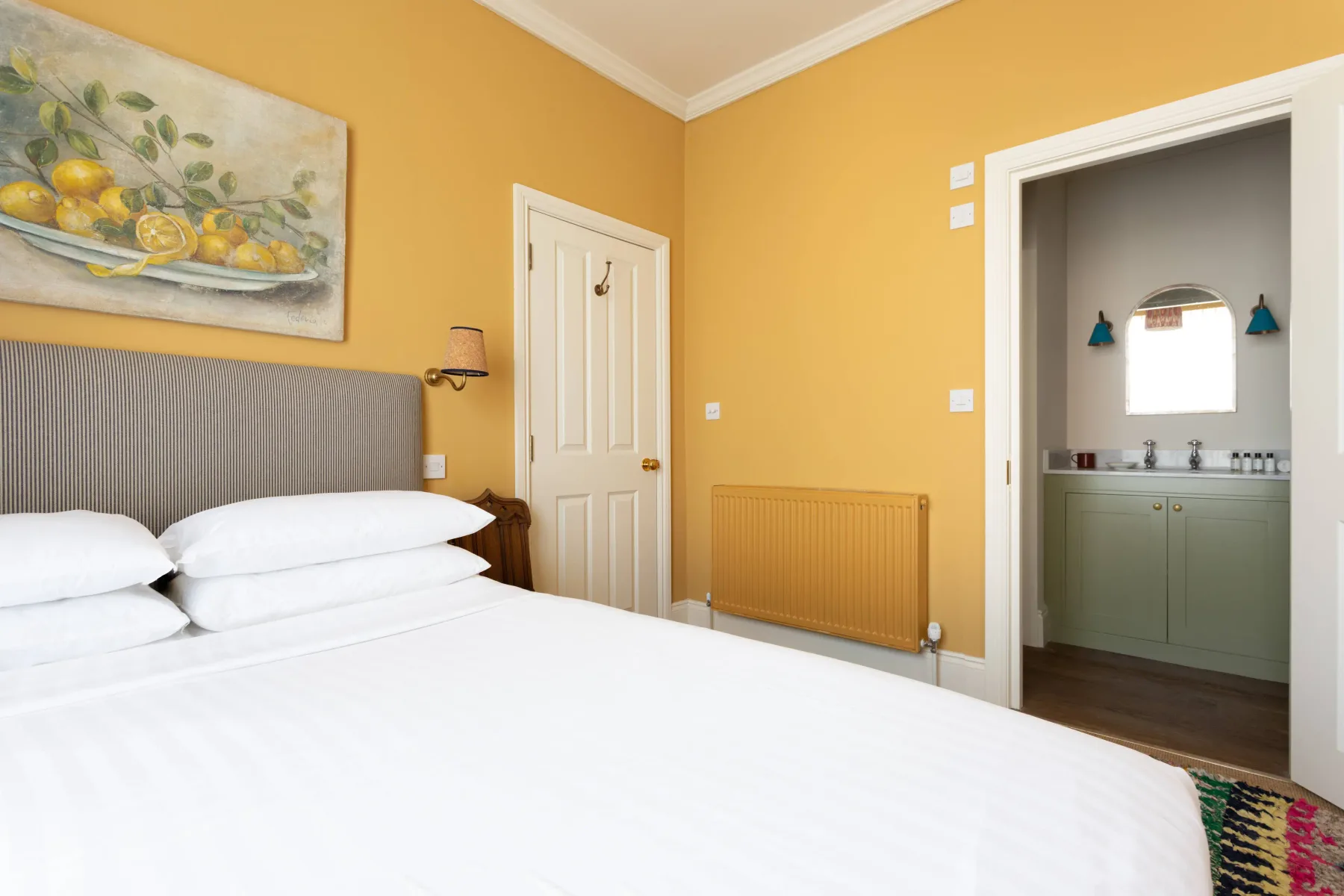 A bedroom with a neatly made bed and an open doorway to a bathroom.