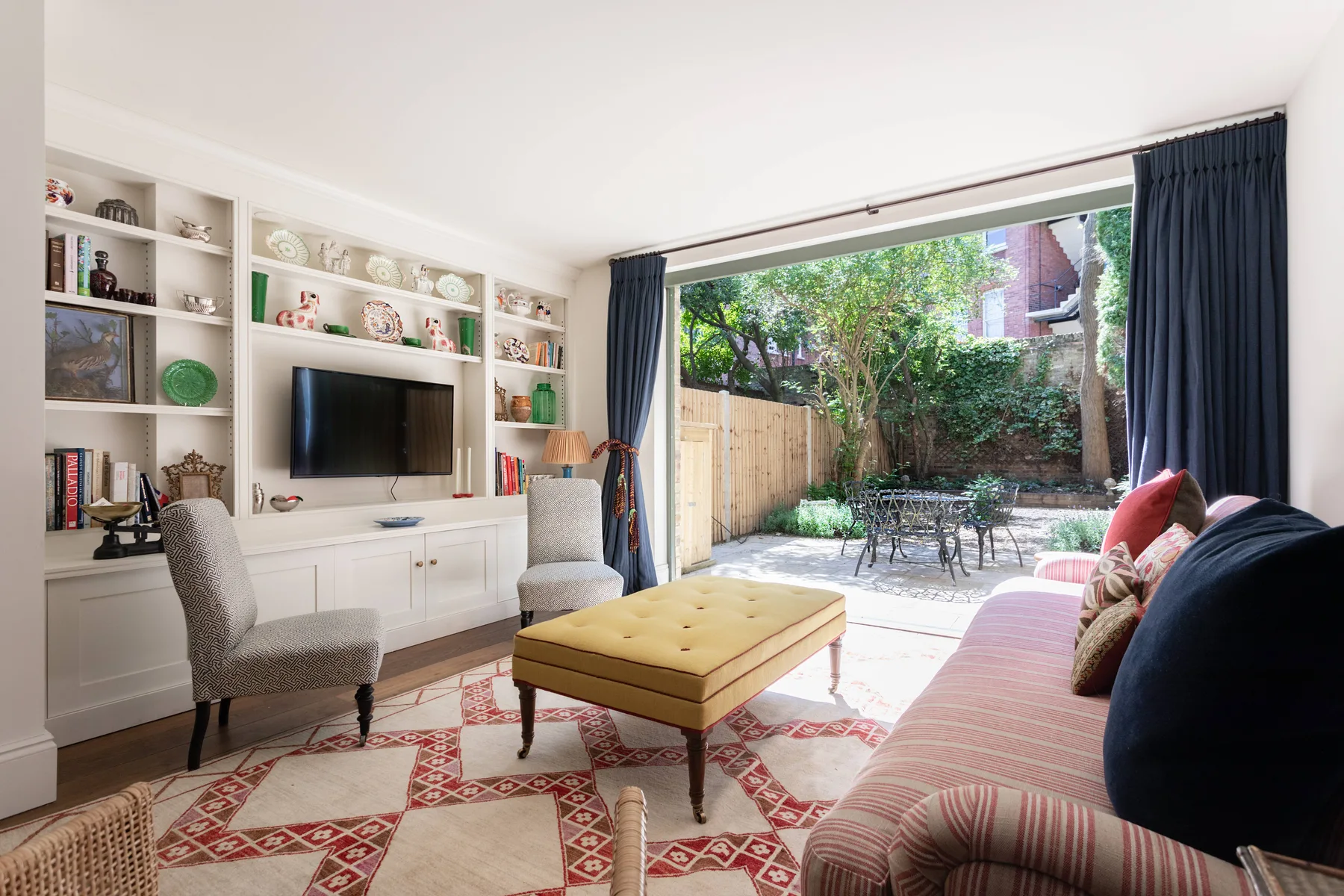 Una sala luminosa da a un patio ajardinado, con estantes empotrados y asientos.