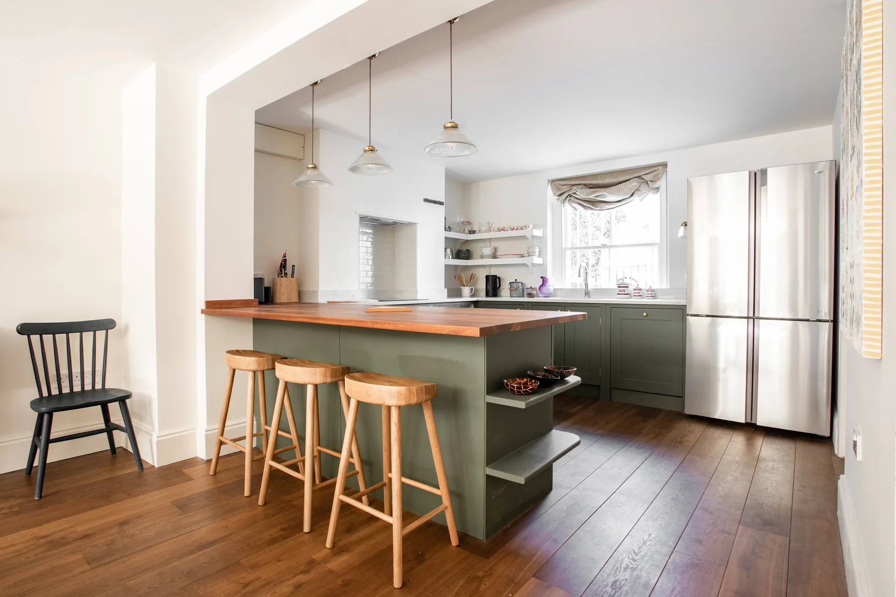 A bright open kitchen with a long island and wooden stools.