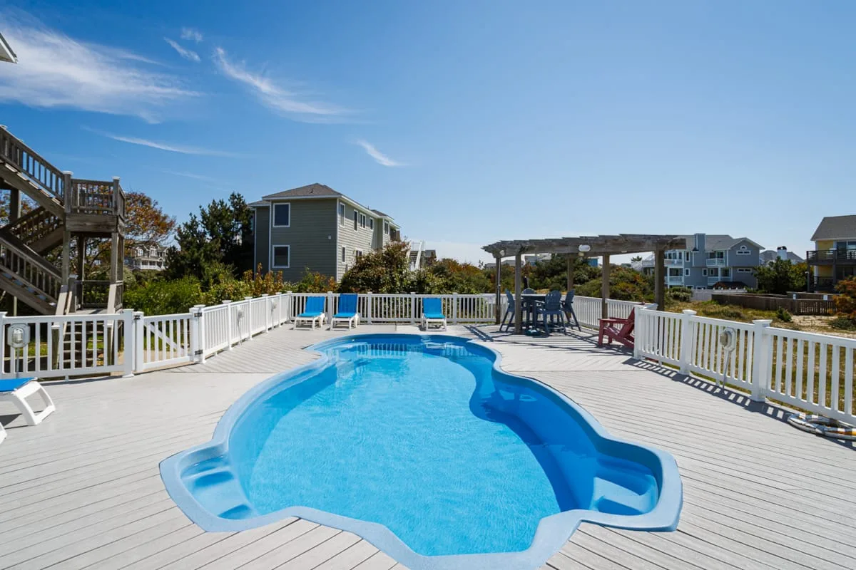 Una piscina al aire libre está sobre una amplia terraza rodeada de barandillas blancas.
