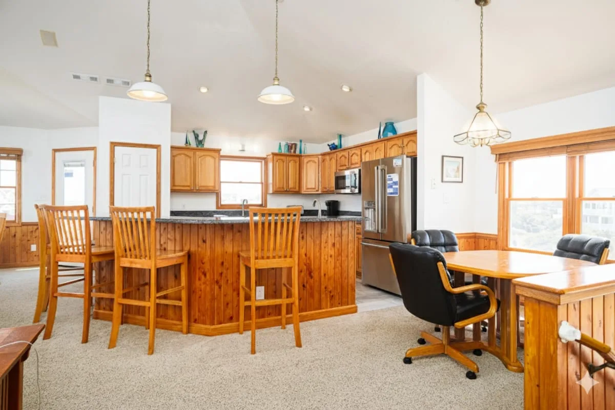 Una cocina y comedor compartidos con gabinetes y mesas de madera.