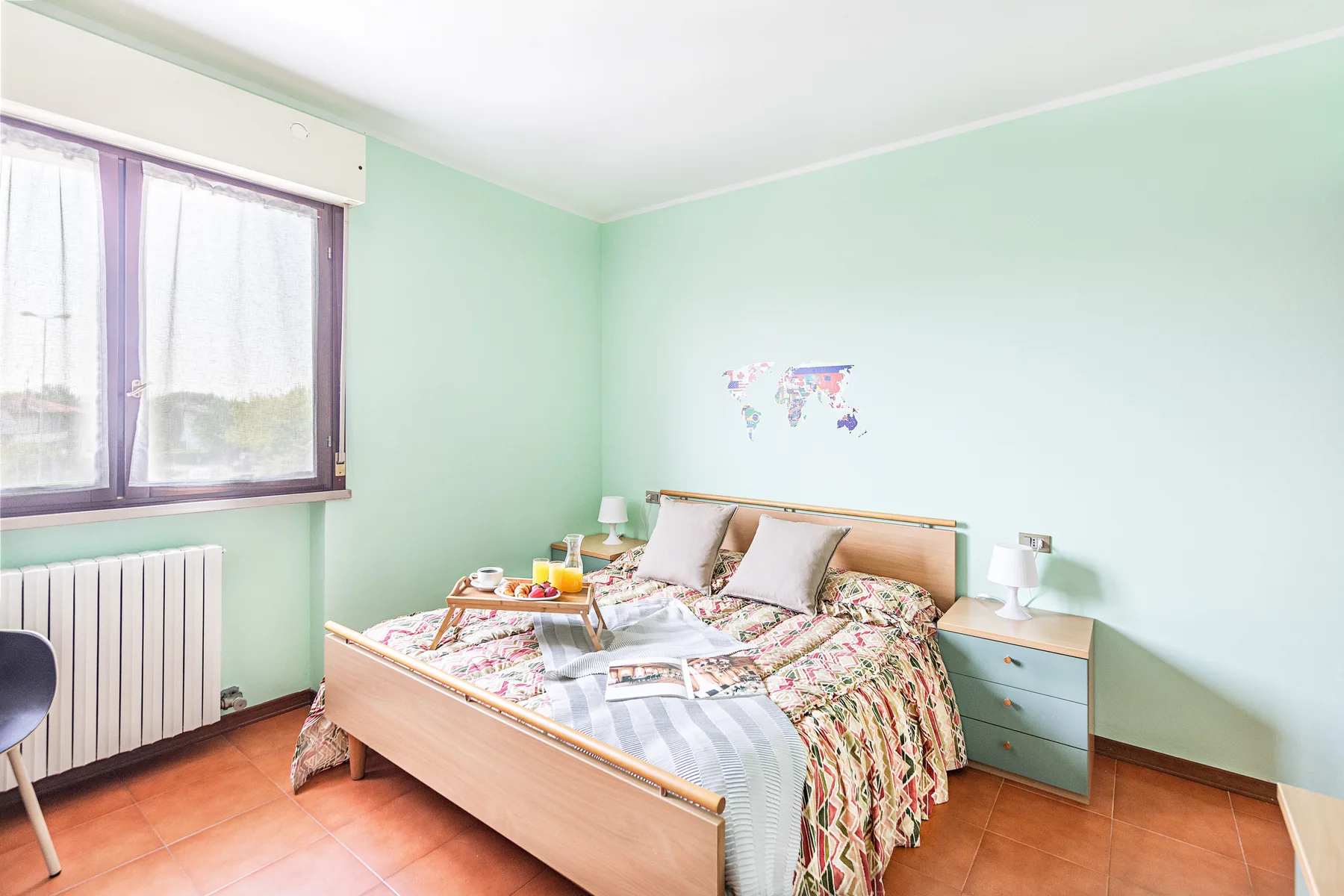 Un dormitorio con una cama, mesitas de noche y una ventana.