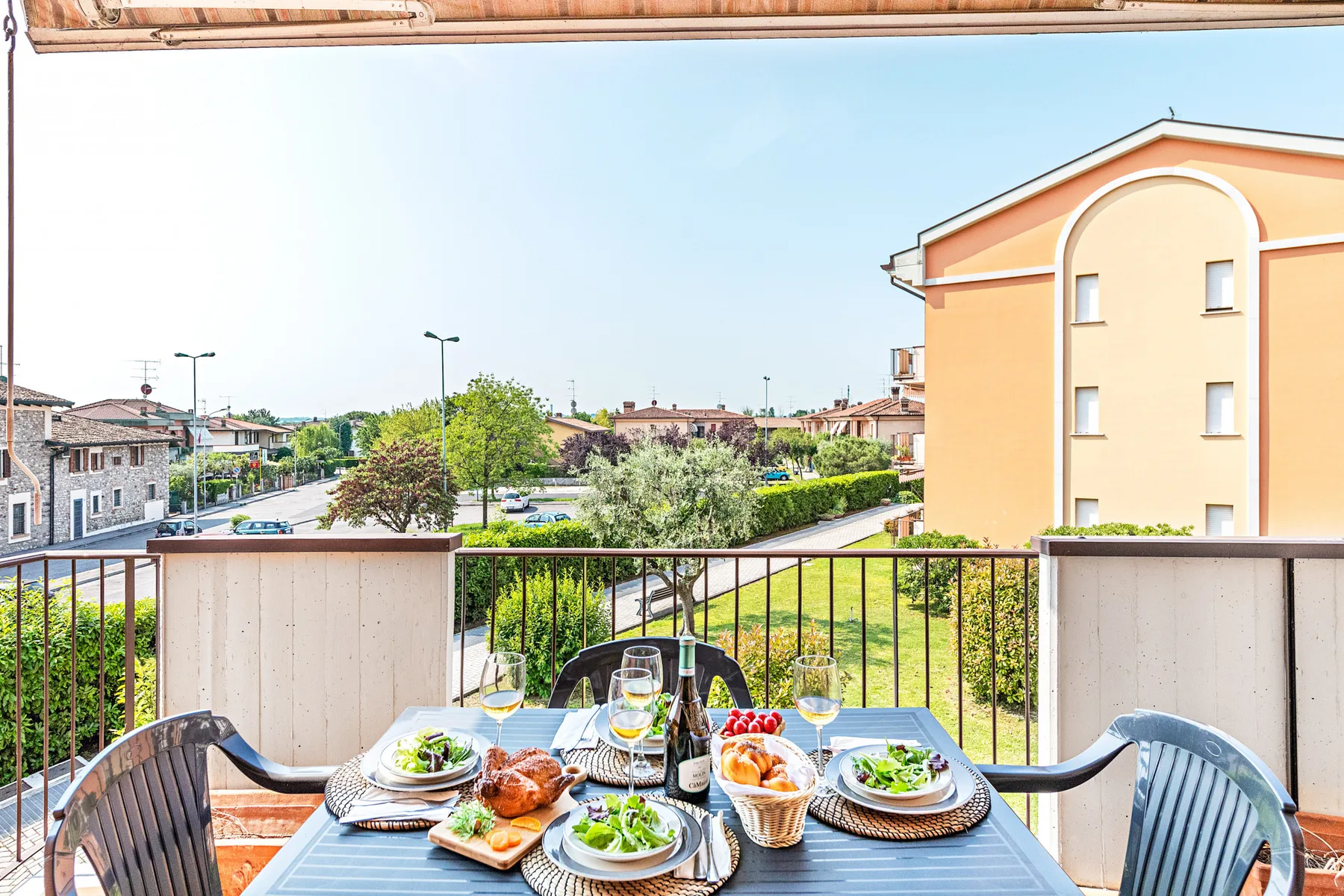 Una zona de comedor en el balcón da a zonas verdes y edificios cercanos.