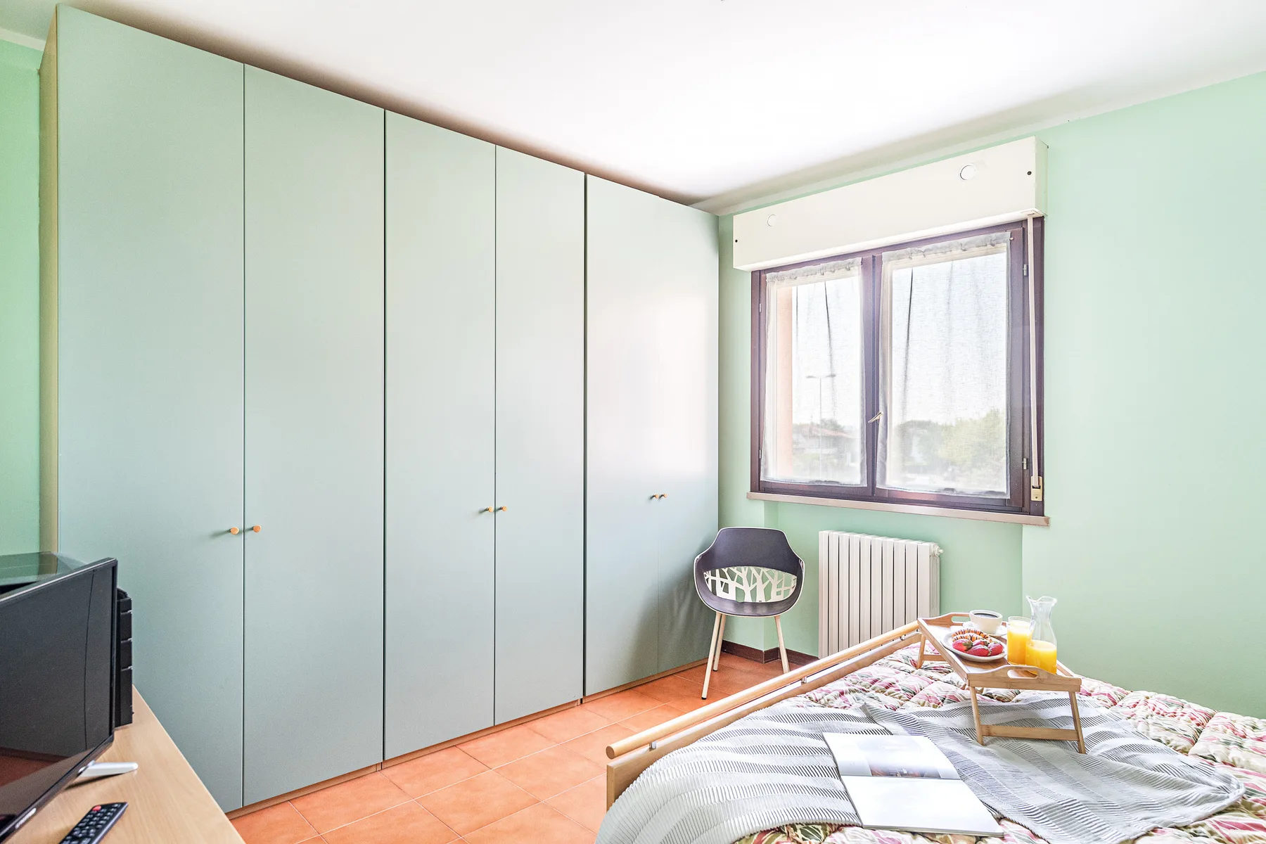 Un dormitorio con armarios empotrados, una ventana y una cama.