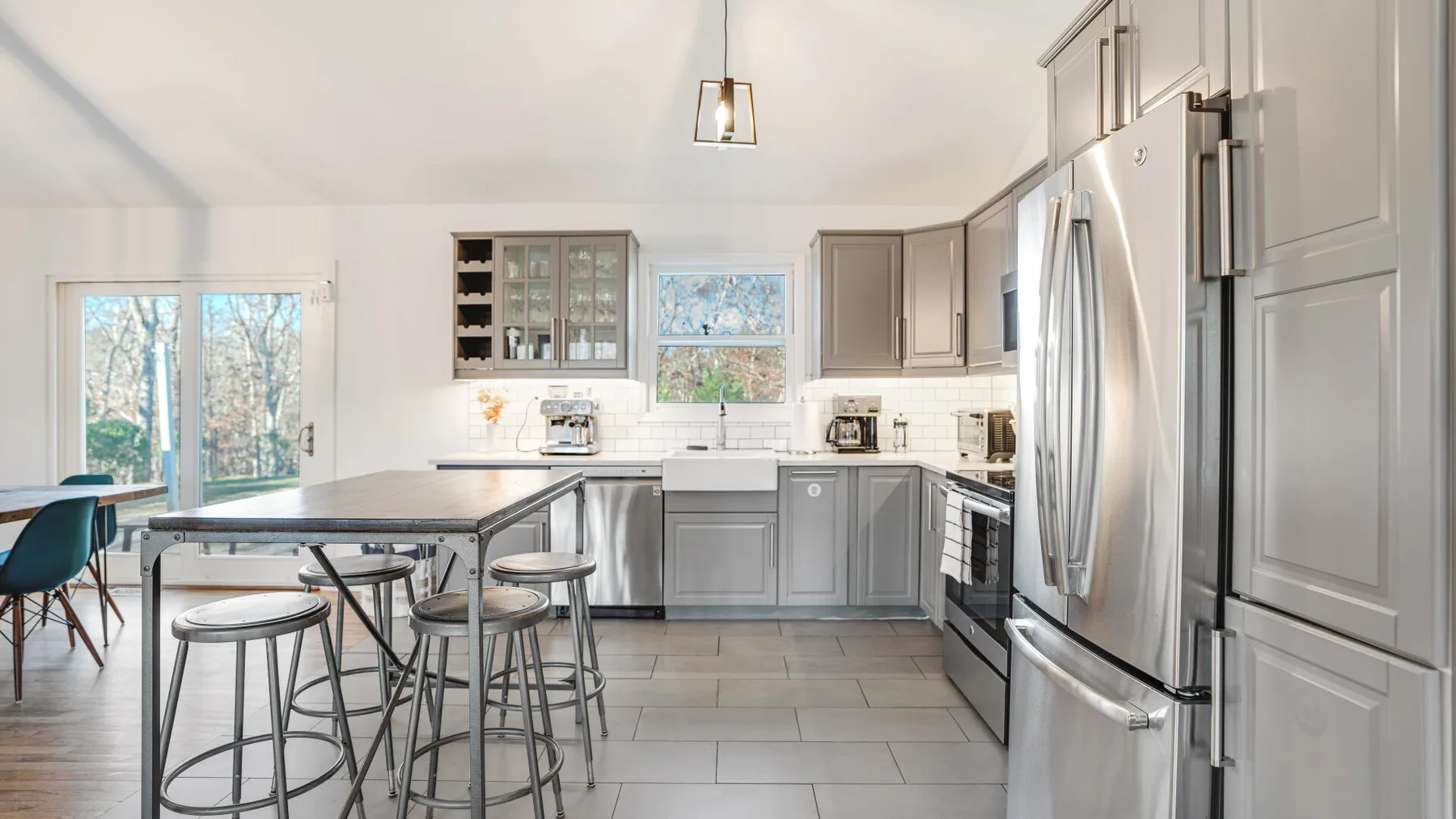 A bright kitchen with gray cabinets, a large island, and stainless steel appliances.