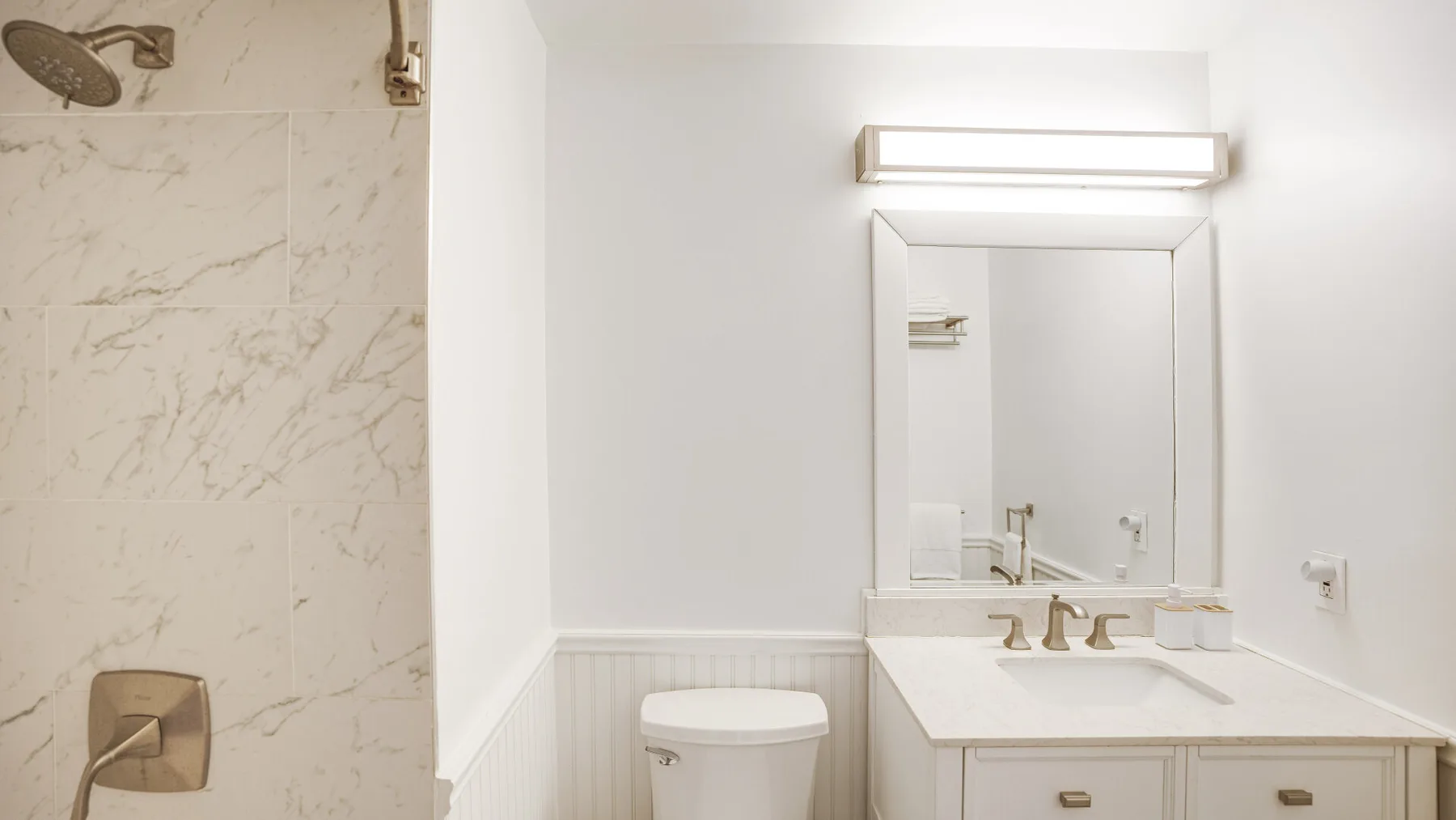A bathroom vanity with a mirror and a tiled shower area.