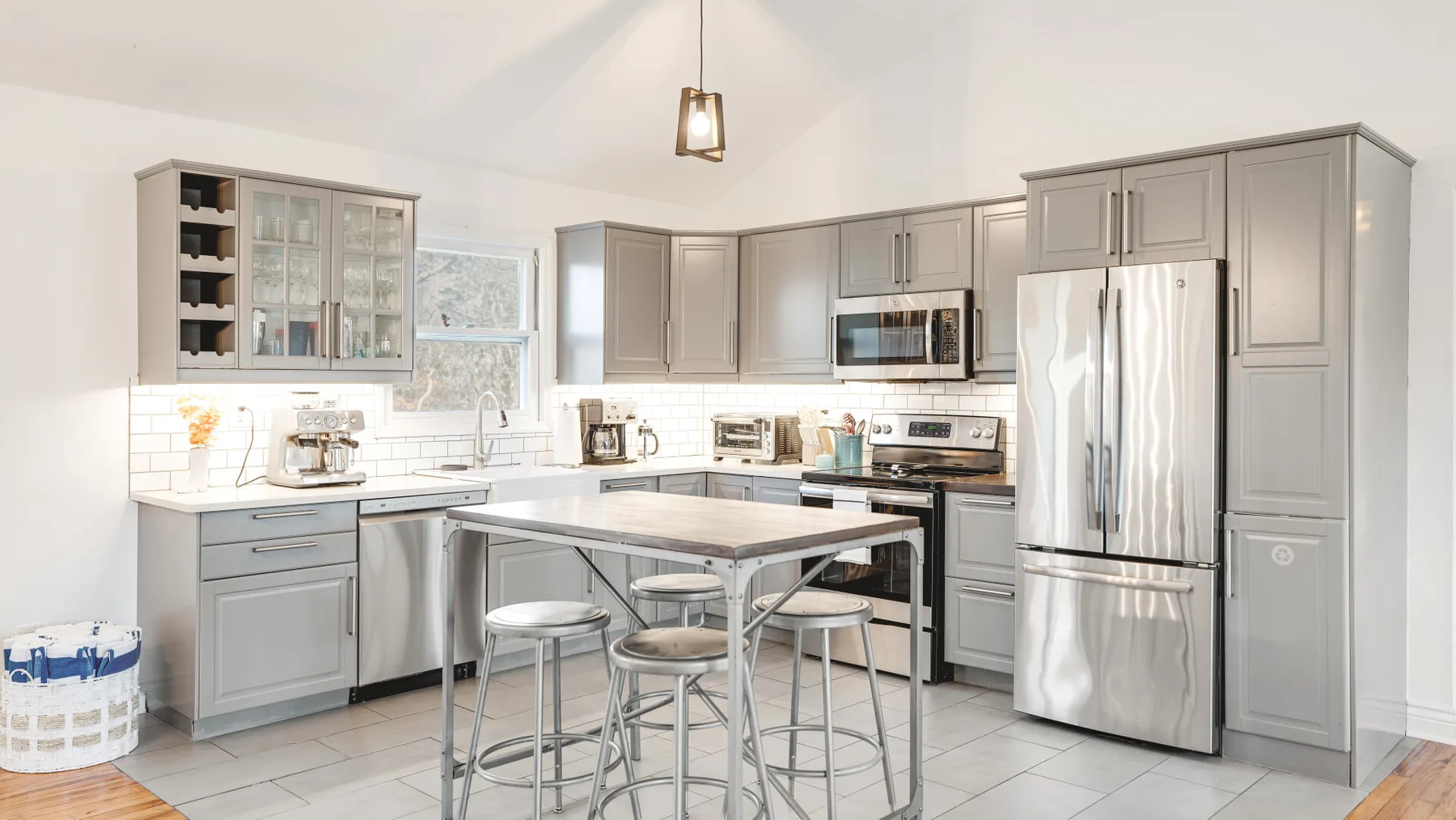A bright kitchen with gray cabinetry, stainless steel appliances, and a central island.
