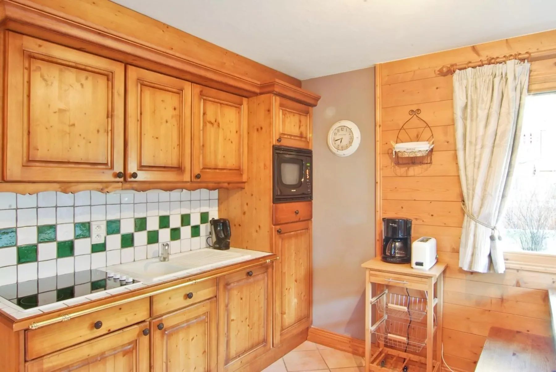 A compact kitchen with wooden cabinets, a tiled backsplash, and a bright window.