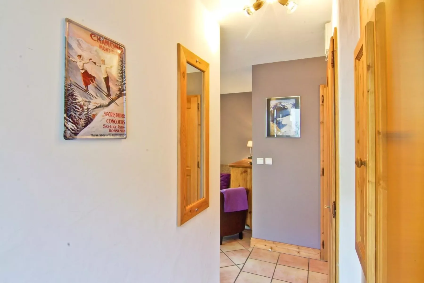 A hallway with framed artwork and open doorways leading into adjacent rooms.