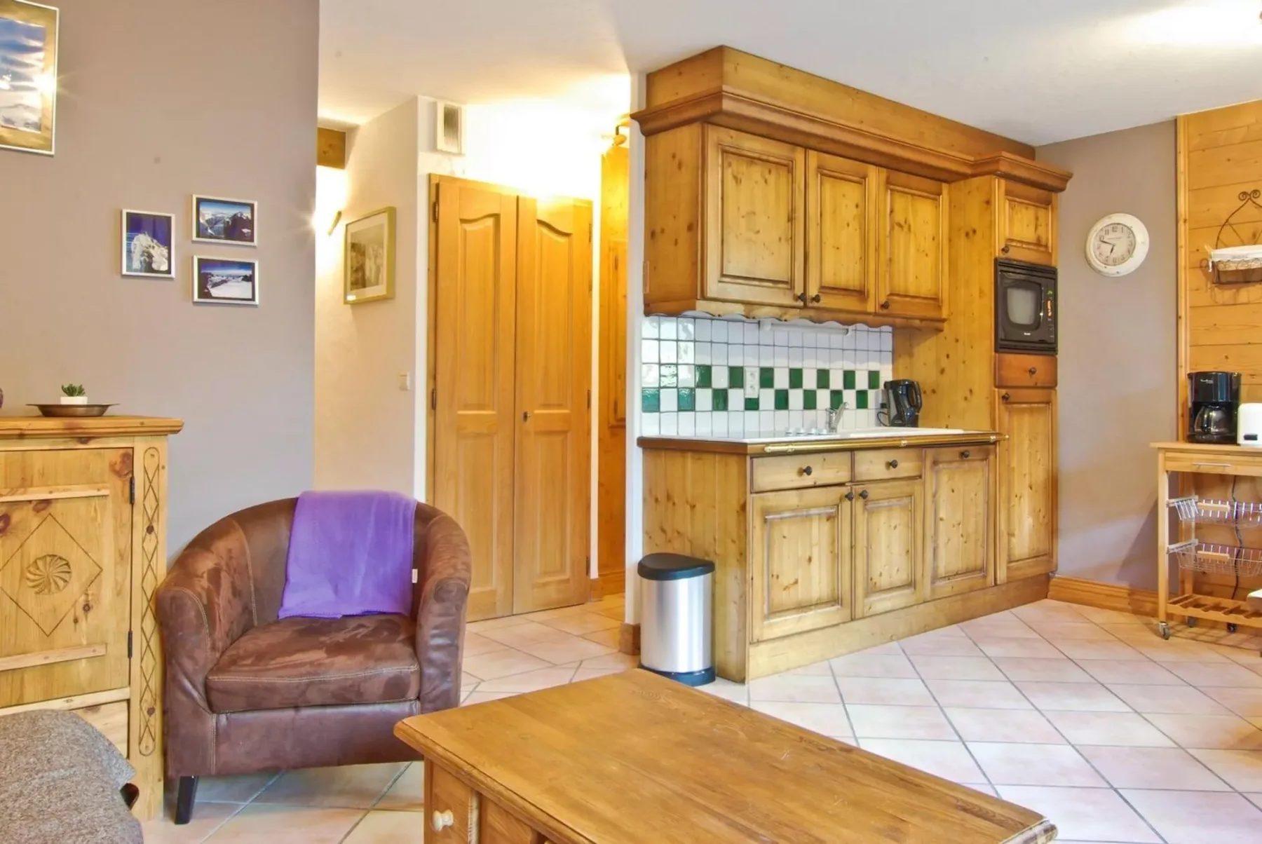A warm wood-paneled kitchen with a tiled backsplash and nearby seating.