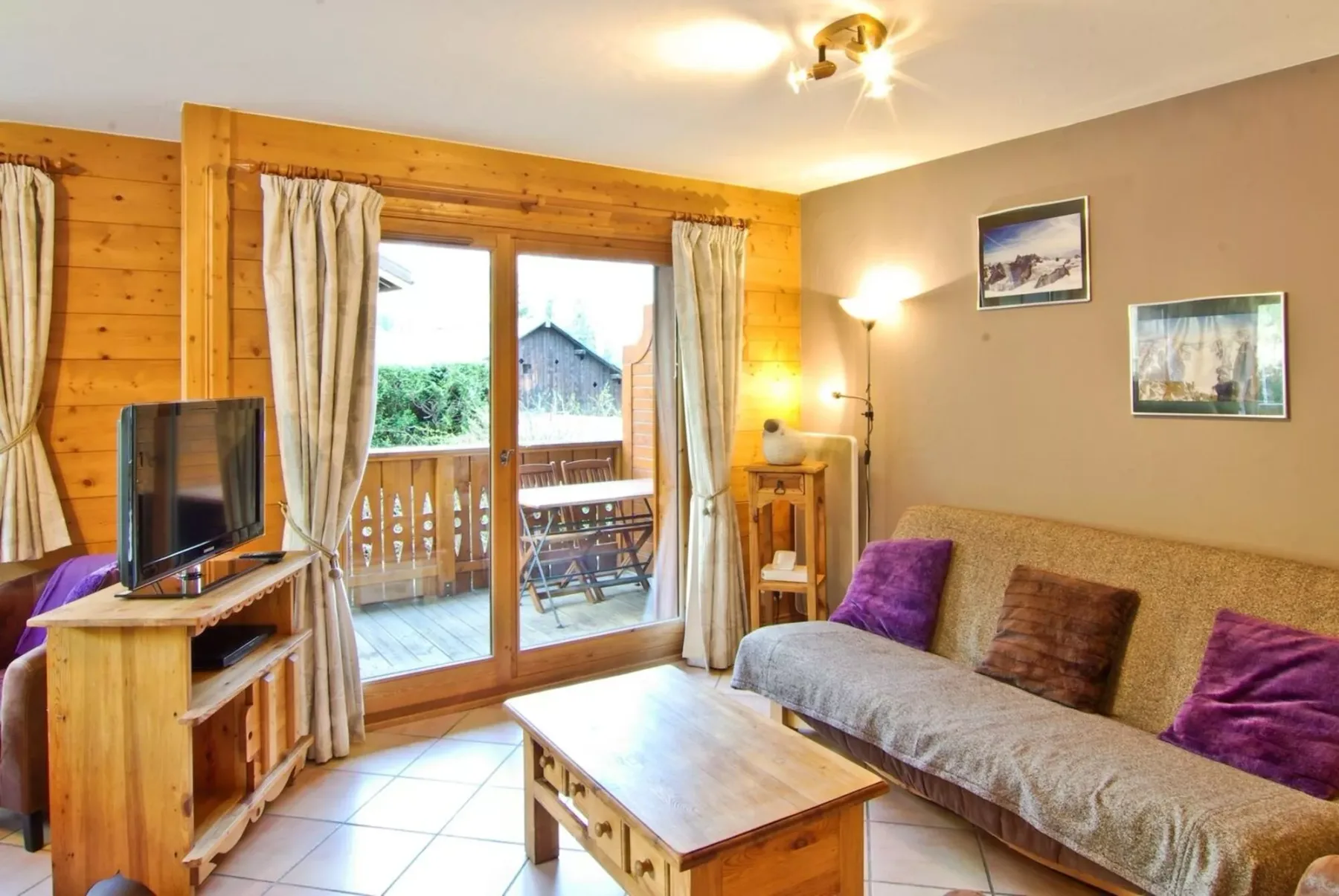 A wood-paneled living room with a sofa and glass doors opening onto a balcony.