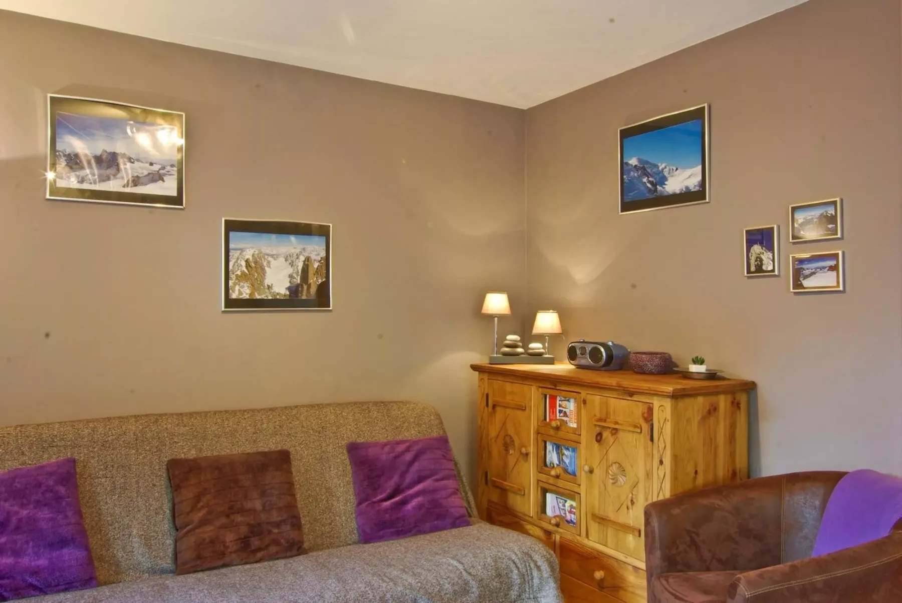 A living room with a wooden cabinet, framed pictures, and seating.