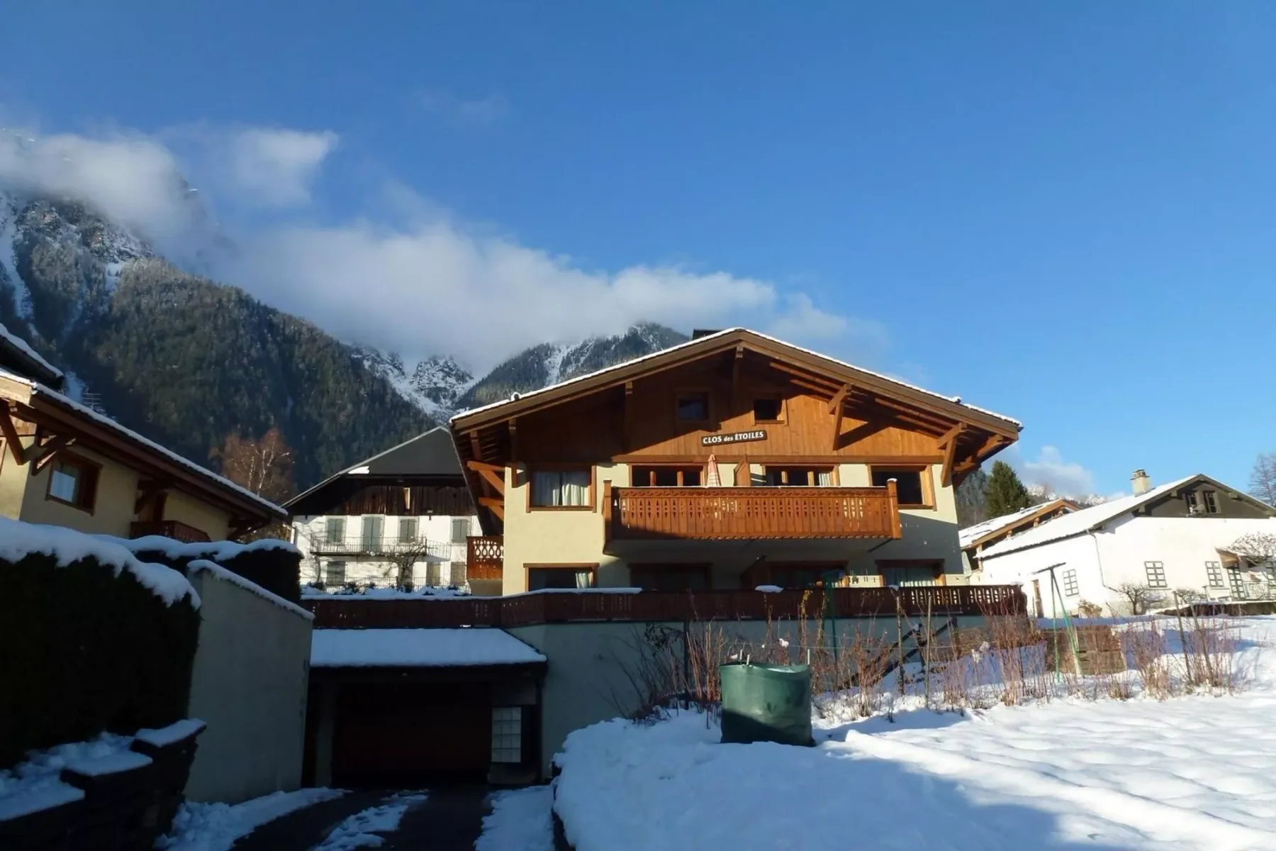 A chalet-style building sits in a snowy mountain village beneath a blue sky.