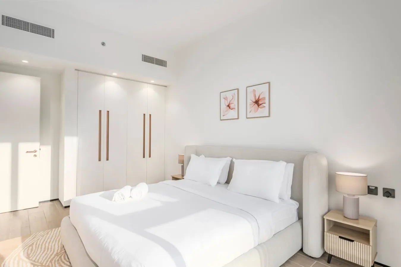 Un dormitorio luminoso con una cama bien hecha y armarios empotrados.